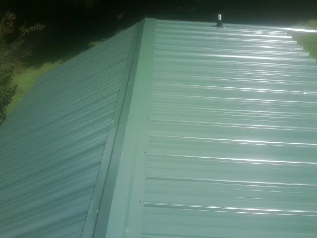 New green metal panels meeting at the ridge of a roof — Flat Roof Repair work by our crew in Whitehouse