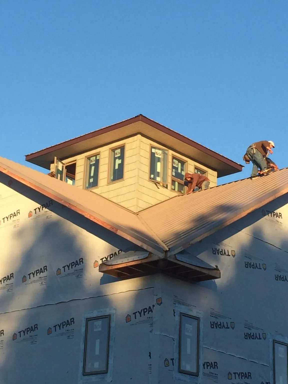 Roofers working around a rooftop cupola on a new metal roof at sunset — Roof Waterproofing in Whitehouse by Roofing Brothers